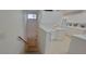 Bright, all-white kitchen adjacent to staircase with tiled flooring and access to basement at 6834 Fairview Ter # 6834, Bradenton, FL 34203