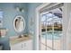 Charming bathroom featuring blue walls, white vanity, and a glimpse of the pool area through the door at 6955 Stetson Street Cir, Sarasota, FL 34243