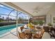 Inviting screened lanai with dining table, ceiling fan, and view of the pool and beautiful landscaping at 6955 Stetson Street Cir, Sarasota, FL 34243
