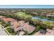 Aerial view showcasing a luxurious home with a terracotta roof situated near a golf course and a tranquil lake at 7210 Desert Ridge Gln, Lakewood Ranch, FL 34202