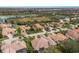 A high angle showcases tile roofed homes, set amongst a background of a lake and golf course in a planned community at 7210 Desert Ridge Gln, Lakewood Ranch, FL 34202