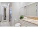 A clean bathroom with a white vanity, tan countertops, a large mirror, and a glass door to the shower at 7210 Desert Ridge Gln, Lakewood Ranch, FL 34202