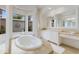 Bright bathroom featuring an oval tub with jets, tan tile flooring and a large window with a lovely view at 7210 Desert Ridge Gln, Lakewood Ranch, FL 34202