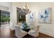 Elegant dining area with a glass table, tufted chairs, chandelier, and backyard views at 7210 Desert Ridge Gln, Lakewood Ranch, FL 34202
