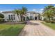 A picturesque home exterior featuring a brick driveway, manicured lawn, and mature palm trees at 7210 Desert Ridge Gln, Lakewood Ranch, FL 34202