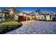 Elegant two-story home showcasing stone accents, lush landscaping, and a paved driveway leading to a three-car garage at 7706 Desoto Memorial Hwy, Bradenton, FL 34209