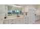 Primary bathroom featuring double sinks, large mirrors, white cabinetry and a separate glass-enclosed shower at 7706 Desoto Memorial Hwy, Bradenton, FL 34209