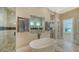 Bright primary bathroom with a soaking tub, view to shower, and travertine flooring at 7706 Desoto Memorial Hwy, Bradenton, FL 34209