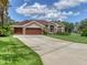 Charming single-Gathering home featuring a three-car garage, well-manicured lawn and stone facade accents at 7723 Heyward Cir, University Park, FL 34201