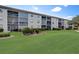 Multi-story building with screened balconies is surrounded by green lawns and mature landscaping at 8735 Olde Hickory Ave # 8303, Sarasota, FL 34238