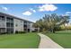 Multi-story condo building with screened balconies set against a lush landscape with mature trees at 8735 Olde Hickory Ave # 8303, Sarasota, FL 34238