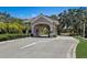 View of the community entrance gate with a tile roof, pillars, and well-manicured landscaping at 8735 Olde Hickory Ave # 8303, Sarasota, FL 34238