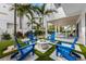 Modern courtyard with a fire pit surrounded by Adirondack chairs and lush landscaping, great for outdoor relaxation at 112 Elm Ave, Anna Maria, FL 34216