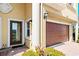 Close-up of the front door and two-car garage, with brick-paved pathway and manicured landscaping at 1318 3Rd Street E Cir, Palmetto, FL 34221