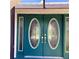 Close up of teal double front doors with decorative glass inserts and gold hardware at 1428 Pine Island Ct, Punta Gorda, FL 33950