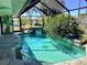 Screened-in pool area with a waterfall feature, lush landscaping, and views of surrounding homes at 1428 Pine Island Ct, Punta Gorda, FL 33950