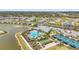 Community amenities aerial view showcasing pool, tennis courts, clubhouse, parking, and surrounding homes near a serene lake at 1524 Remington Trace Dr, Port Charlotte, FL 33953