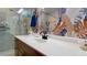 Bathroom sink with a wooden cabinet and an oval mirror with a leaf patterned wallpaper at 1582 Overbrook Rd, Englewood, FL 34223