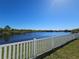 Scenic view of a pond beyond a white vinyl fence in a well-maintained yard at 1819 Redmond Brook Ln, Ruskin, FL 33570
