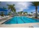 Inviting community pool with palm trees, lounge chairs, umbrellas and blue water at 23085 Banbury Way # 103, Venice, FL 34293