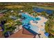 Aerial view of a luxurious outdoor community pool surrounded by palm trees and comfortable lounge seating at 23085 Banbury Way # 103, Venice, FL 34293