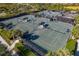 Aerial view of well-maintained tennis courts with shade structures and pristine landscaping at 23085 Banbury Way # 103, Venice, FL 34293