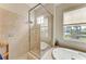Tiled bathroom with a frameless shower, a soaking tub, and a large window providing natural light at 368 Snapdragon Loop, Bradenton, FL 34212