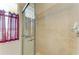 This bathroom features a glass-enclosed shower with neutral tile and a window with translucent red curtains at 368 Snapdragon Loop, Bradenton, FL 34212