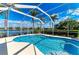A stunning screened pool with clear blue water, surrounded by lush greenery and a beautiful lake view at 368 Snapdragon Loop, Bradenton, FL 34212
