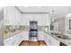 Modern kitchen with stainless steel appliances, white cabinets, granite countertops, and a tile backsplash at 3708 Wayfarer Way, Palmetto, FL 34221