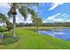 Beautiful backyard featuring a pond, palm trees, and lush green grass overlooking the golf course at 379 Fairway Isles Ln, Bradenton, FL 34212