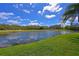 Lush backyard featuring a tranquil pond, vibrant green grass, and clear blue sky, perfect for outdoor enjoyment at 379 Fairway Isles Ln, Bradenton, FL 34212