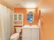 Bright bathroom featuring a toilet, vanity with sink, and a wall-mounted cabinet for additional storage at 3980 Ironwood Cir # 206, Bradenton, FL 34209
