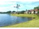 View of community pond with mature trees, green grass, and red tile roofed buildings at 4001 Crockers Lake Blvd # 16, Sarasota, FL 34238