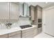 Modern gas cooktop and stainless vent in a kitchen with light wood cabinetry and quartz countertop at 6013 White Mangrove Ln, Bradenton, FL 34210