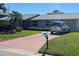 Charming single-story home with a well-maintained lawn, brick driveway, and mature palm trees enhancing curb appeal at 604 Dundee Ln, Holmes Beach, FL 34217