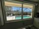 Tranquil backyard pool area as seen through a window, featuring a screened-in pool, patio furniture, and lush landscaping at 604 Dundee Ln, Holmes Beach, FL 34217