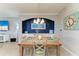 Dining room with a wooden table set for four, elegant chandelier, and coastal-themed decor at 7004 Grand Estuary Trl # 101, Bradenton, FL 34212