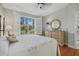 Sun-filled bedroom featuring a large window with views of a lush green space and hardwood floors at 7416 Botanica Pkwy # 103, Sarasota, FL 34238