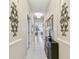 Bright hallway featuring decorative wall art, white tile floors, and a stylish console table with floral arrangement at 803 Fairwaycove Ln # 106, Bradenton, FL 34212