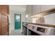 A well-equipped laundry room with a blue door, white cabinets, and modern washer and dryer units at 101 Base E Ave # 101 103, Venice, FL 34285
