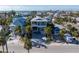 Aerial view of a stylish coastal home surrounded by palm trees and other beach houses in a residential neighborhood at 108 Magnolia Ave, Anna Maria, FL 34216