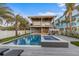 Backyard oasis featuring a pool, spa, and outdoor lounge area surrounded by swaying palm trees at 108 Magnolia Ave, Anna Maria, FL 34216