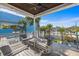 Inviting covered balcony with comfortable seating, scenic palm tree views, and a glimpse of the pool at 108 Magnolia Ave, Anna Maria, FL 34216