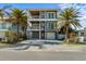 Beach house with dual balconies, circular windows, a red door, and mature palm trees at 108 Magnolia Ave, Anna Maria, FL 34216