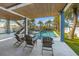 Covered outdoor patio overlooking a beautiful swimming pool and spa surrounded by palm trees and lounge chairs at 108 Magnolia Ave, Anna Maria, FL 34216