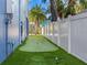 Backyard putting green surrounded by lush grass and a white fence, perfect for golf enthusiasts at 108 Magnolia Ave, Anna Maria, FL 34216