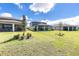 Wide backyard featuring a covered patio, lush green lawn, and neatly arranged landscaping at 11531 Moonsail Dr, Parrish, FL 34219