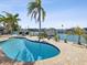 A waterfront backyard with a refreshing pool and a boat dock in a tropical setting at 12000 4Th St E, Treasure Island, FL 33706