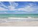 Waves wash up on a serene sandy beach with blue skies above at 1211 Gulf Of Mexico Dr # 207, Longboat Key, FL 34228